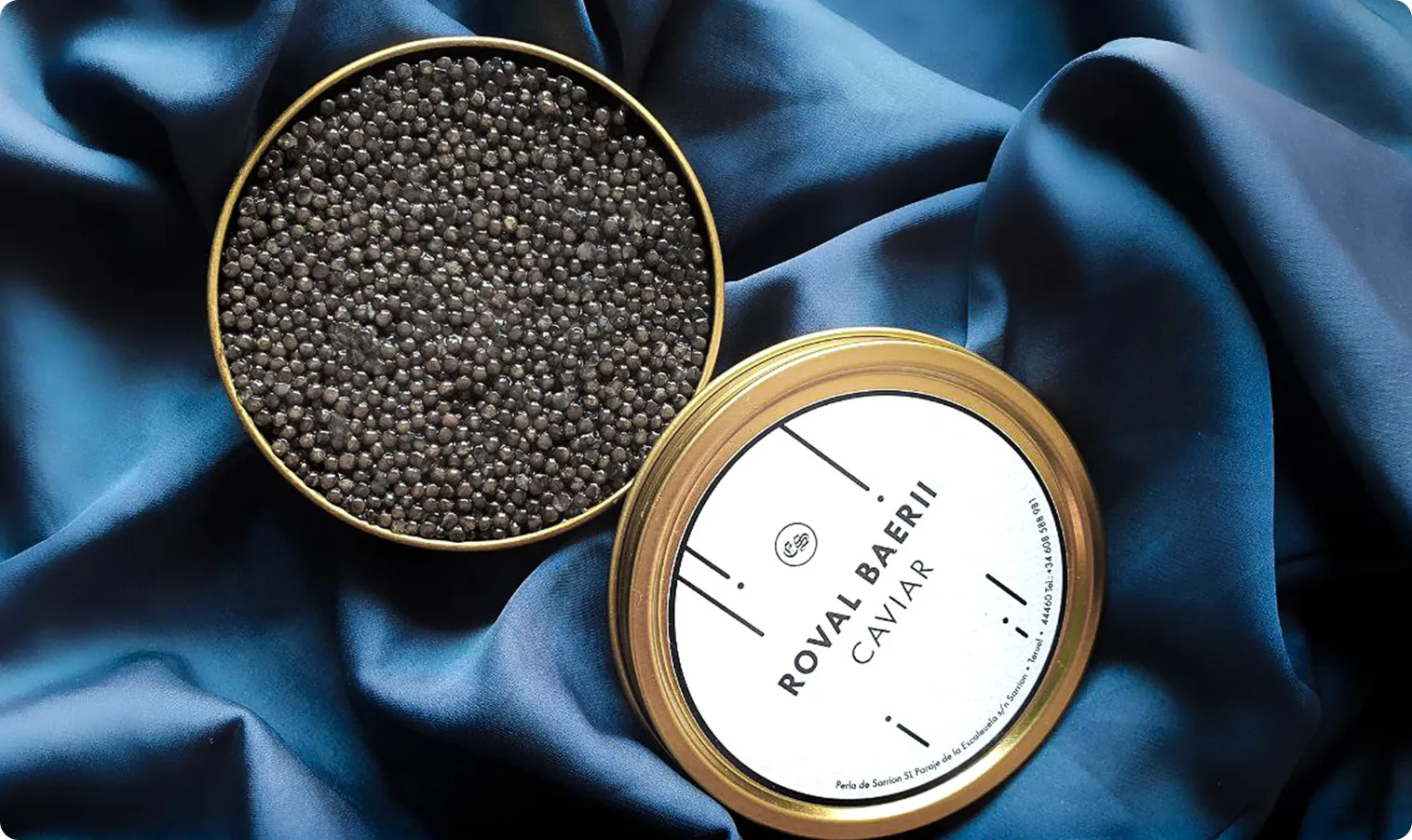 Lata de caviar Negin Gourmet abierta sobre seda azul